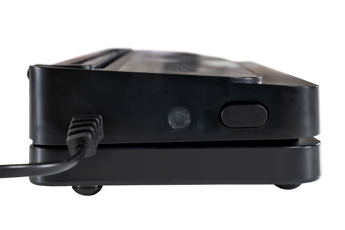 Nahaufnahme der Seite des Unold Vakuumierer Food Saver Black, die sein Netzkabel, einen runden Knopf und einen rechteckigen Knopf an der Seite zeigt, während er auf einer flachen Oberfläche liegt.