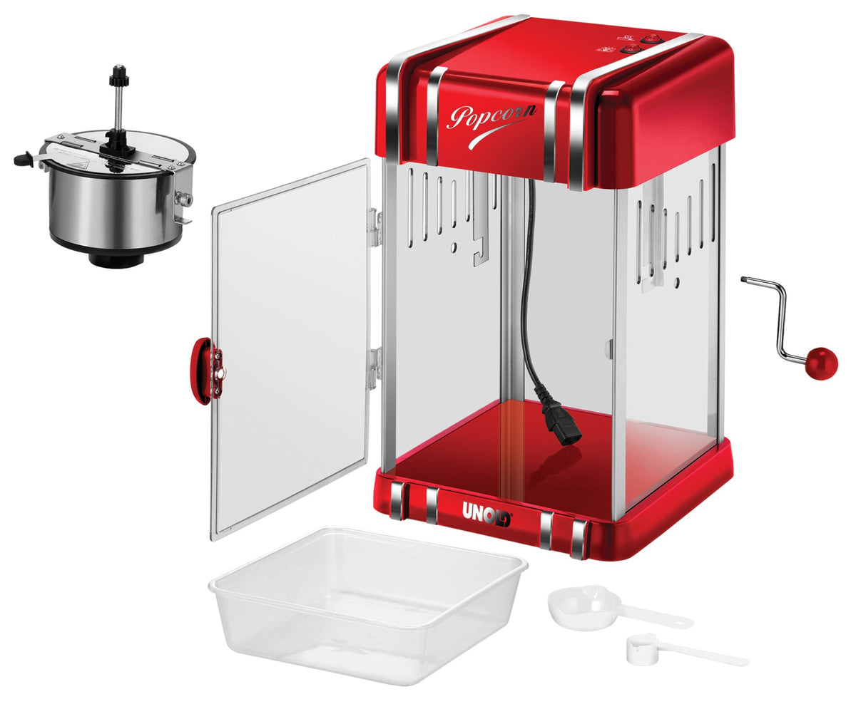 Der Unold Popcornmaker Retro in Rot und Silber verfügt über ein sichtbares Netzkabel, eine seitliche Kurbel, eine offene Tür, einen abnehmbaren Kessel, ein Kunststofftablett, einen Messbecher und einen separat abgebildeten Löffel.