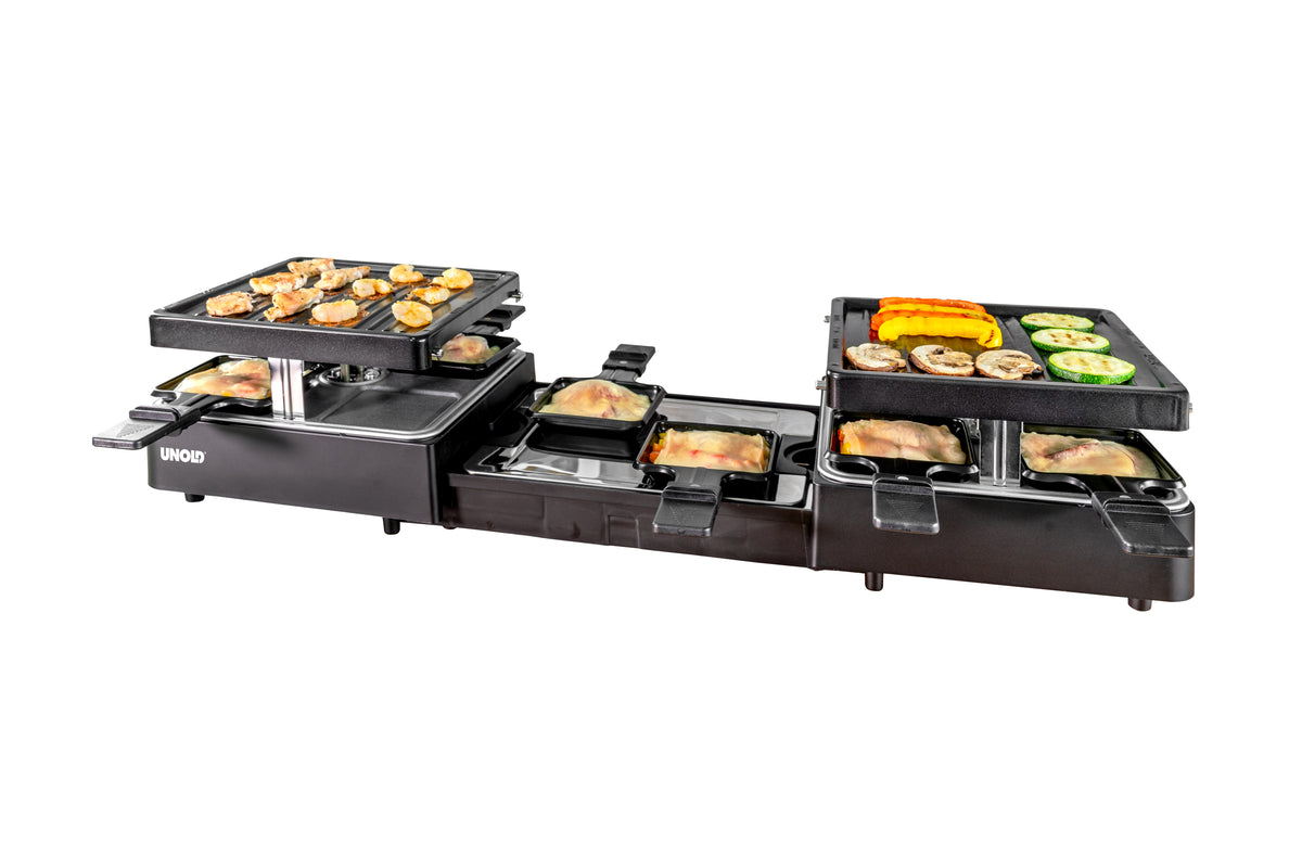 Der Unold Raclette Extendable ist ein schwarzer Elektrogrill mit zwei Heizbereichen, darunter befinden sich kleine Pfännchen, auf denen verschiedene Lebensmittel wie Gemüse, Pilze und Fleisch gegart werden, beispielsweise oben und in den Pfännchen.