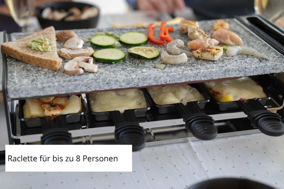 Das Unold Raclette Delice Basic besteht aus Gemüse, Garnelen, Hähnchen und Brot obenauf und darunter aus geschmolzenem Käse. Auf dem deutschen Etikett steht: „Raclette für bis zu 8 Personen“.