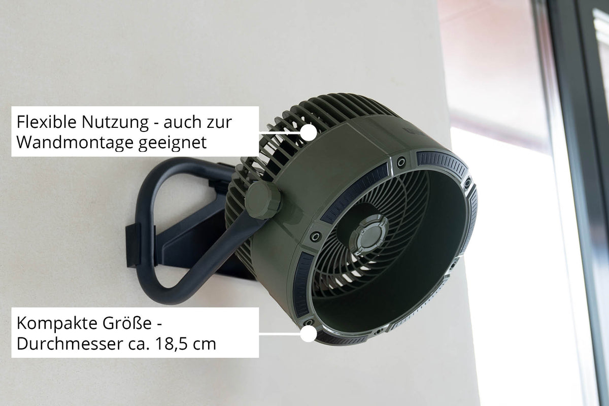 Der Unold Akkuventilator Outdoor ist ein kompakter, dunkelgrün-schwarzer Ventilator mit ca. 18,5 cm Durchmesser, konzipiert für den flexiblen Einsatz und die einfache Wandmontage, wie im deutschen Text dargestellt, in Fensternähe.