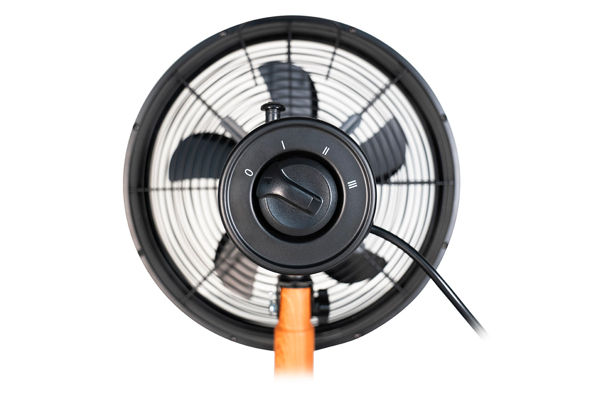 Nahaufnahme des Unold Tischventilators Black Steel, eines schwarzen elektrischen Ventilators mit drei Geschwindigkeitsstufen, rundem Gitter und zentralem Geschwindigkeitsregler auf einem eleganten Holzständer, von vorne betrachtet.