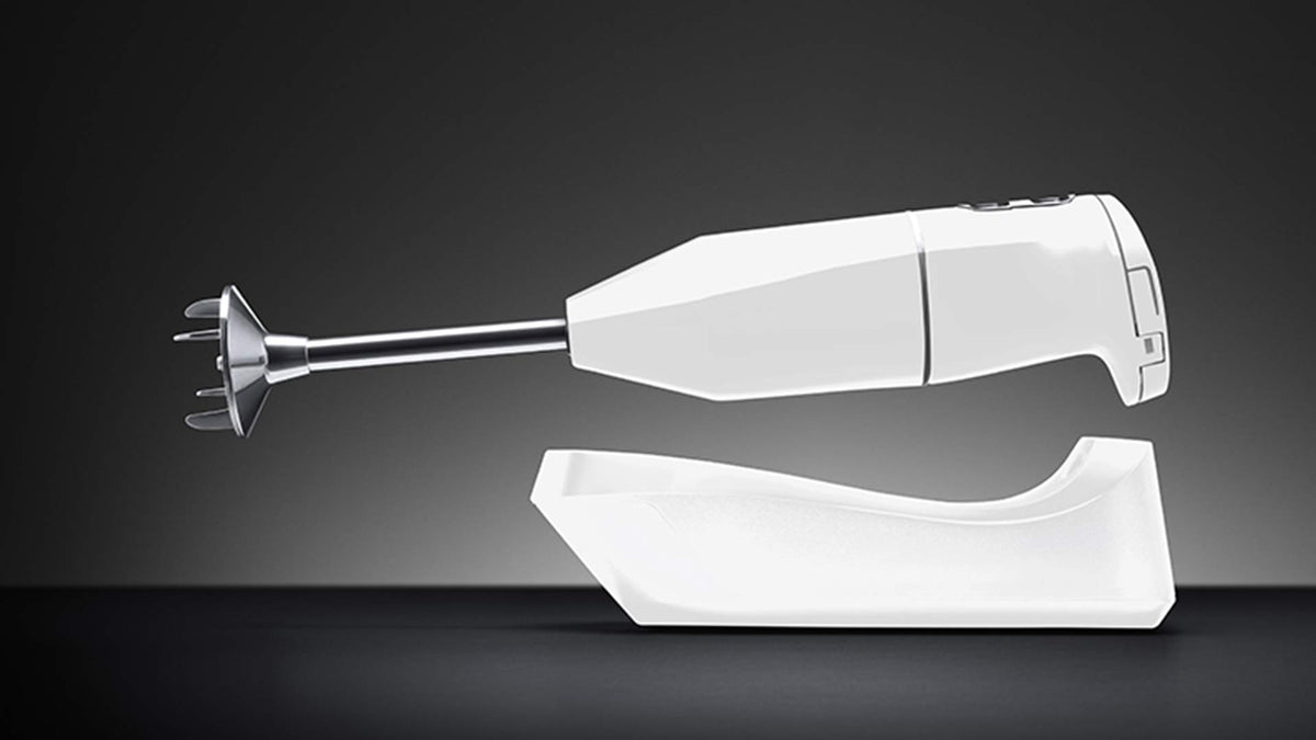 Ein weißer Stabmixer steht auf einem passenden weißen Ständer vor einem schlichten, dunklen Hintergrund. Der Mixer ist horizontal positioniert und unterstreicht sein schlankes, modernes Design.