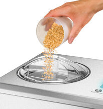 Eine Hand schüttet Zutaten in den geöffneten Deckel der Unold B-Ware Eismaschine Nobile 2 L, einer Eismaschine aus Edelstahl.