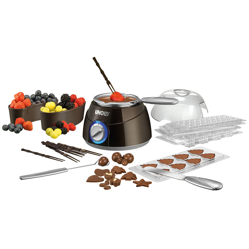 Das Unold Chocolatier-Set umfasst einen Schmelztiegel, Schokoladenformen, zwei Metallutensilien, Schalen mit frischen Beeren, Pralinen in verschiedenen Formen und Schokoladenstäbchen – alles auf weißem Hintergrund.